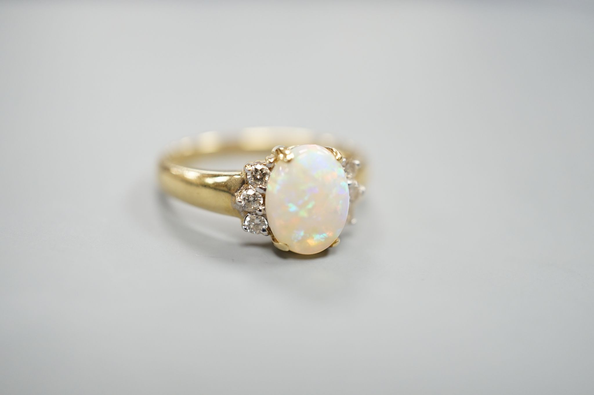 A modern 14k yellow metal, oval white opal and six stone diamond set cluster ring, size N, gross weight 2.9 grams.